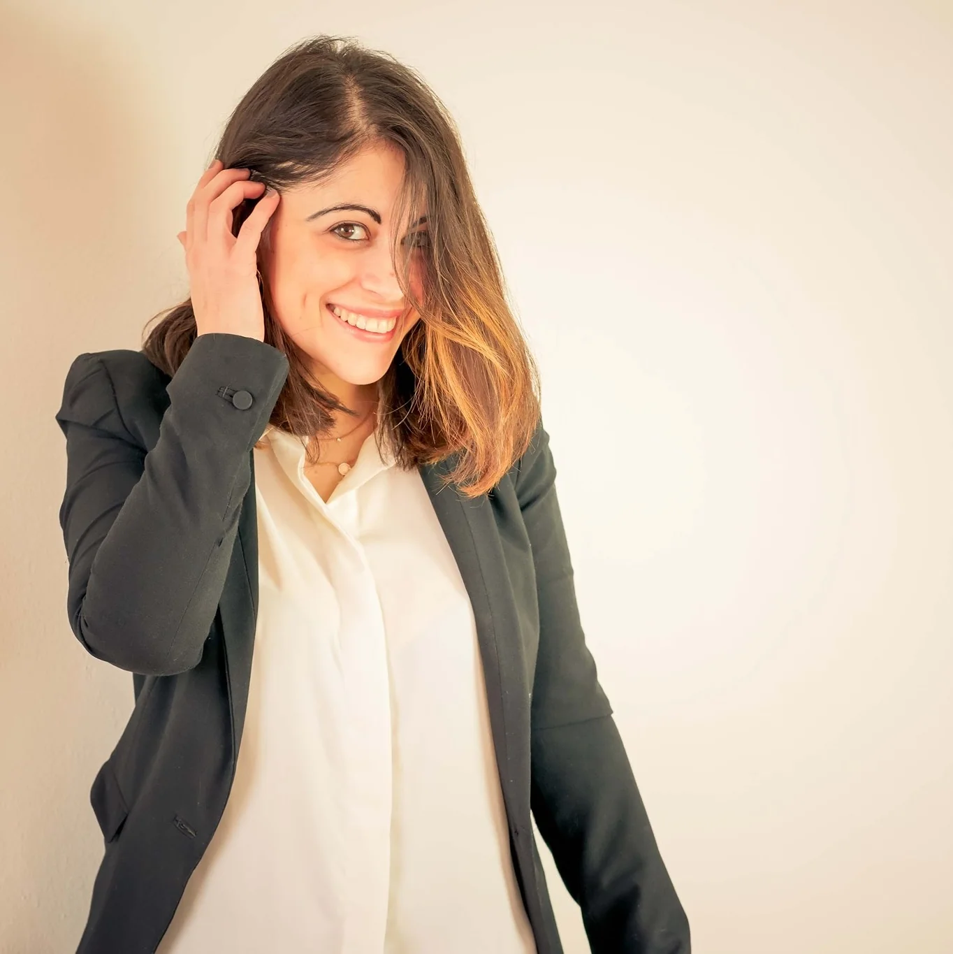 Tiziana in giacca nera sorride con la mano tra i capelli