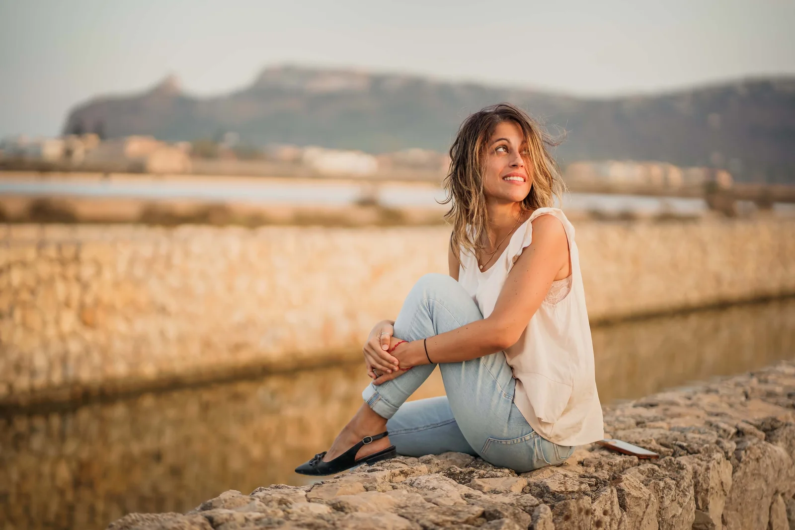 Tiziana seduta su un muretto in riva allo stagno, a Cagliari